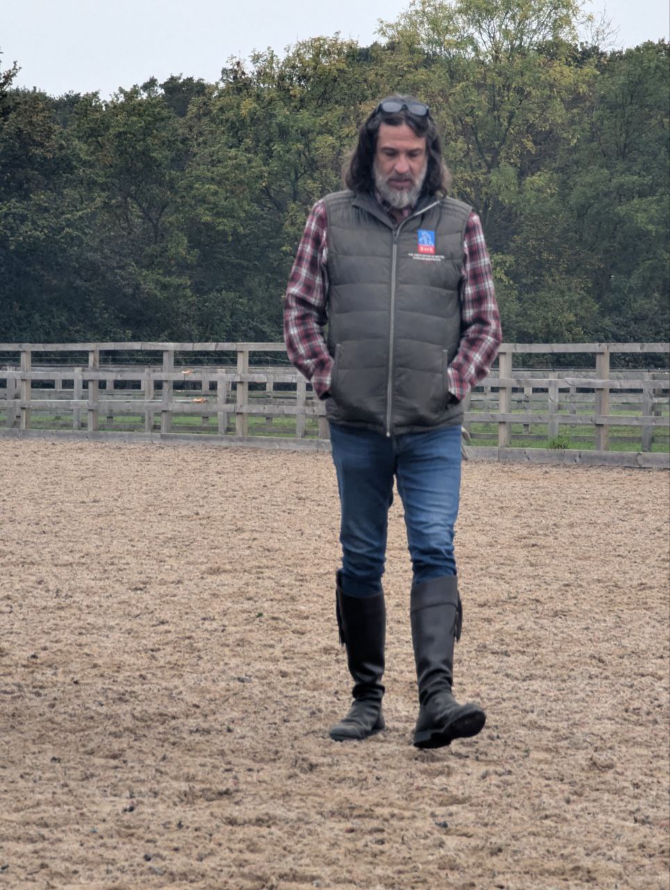“Isaac Ares walking thoughtfully in the arena, author of ‘Cardboard Piaffe,’ a biomechanical analysis on rhythm, collection, and the truth behind modern dressage performance.”